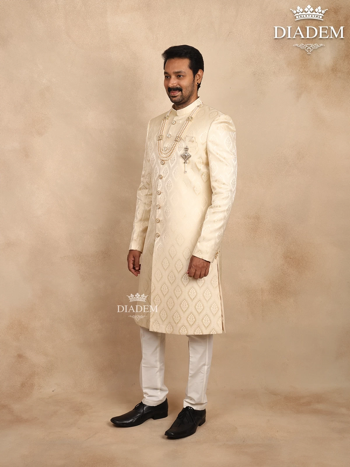Cream Raw Silk Sherwani Suit Adorned With Floral Embroidery, Paired With Brooch And Bead Mala